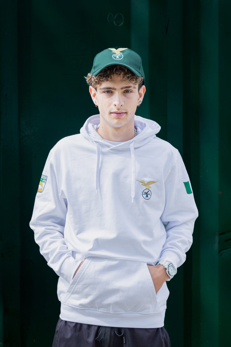 Ragazzo con felpa bianca con cappuccio del Campo Scuola e cappellino verde