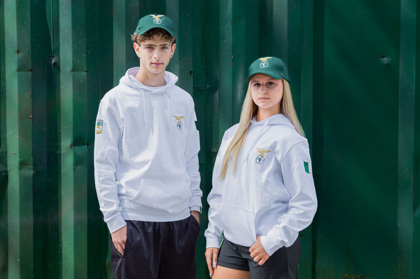 Ragazzo e ragazza indossano la felpa bianca con cappuccio e il cappellino verde