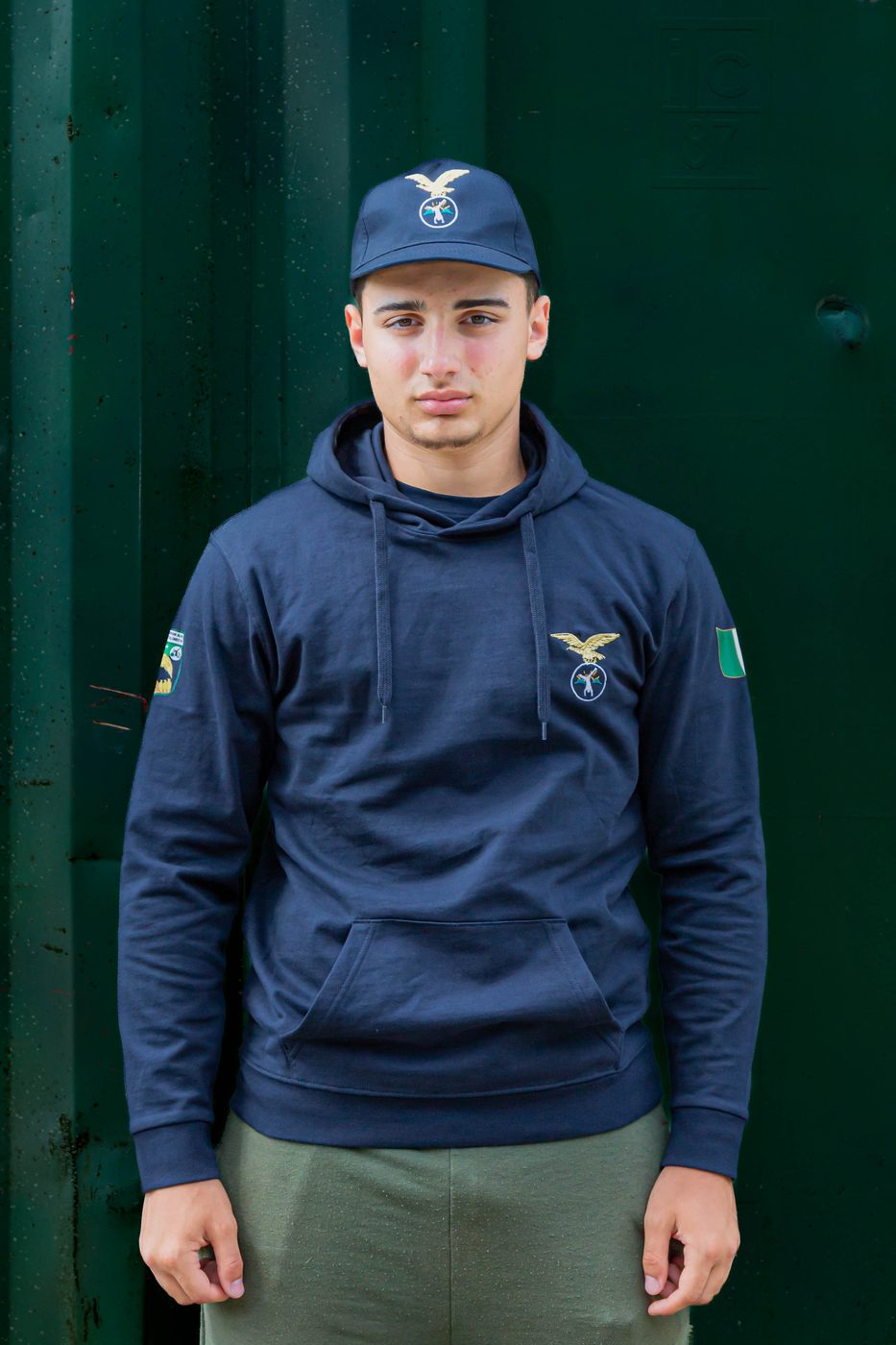 Ragazzo con felpa blu con cappuccio del Campo Scuola e cappellino blu