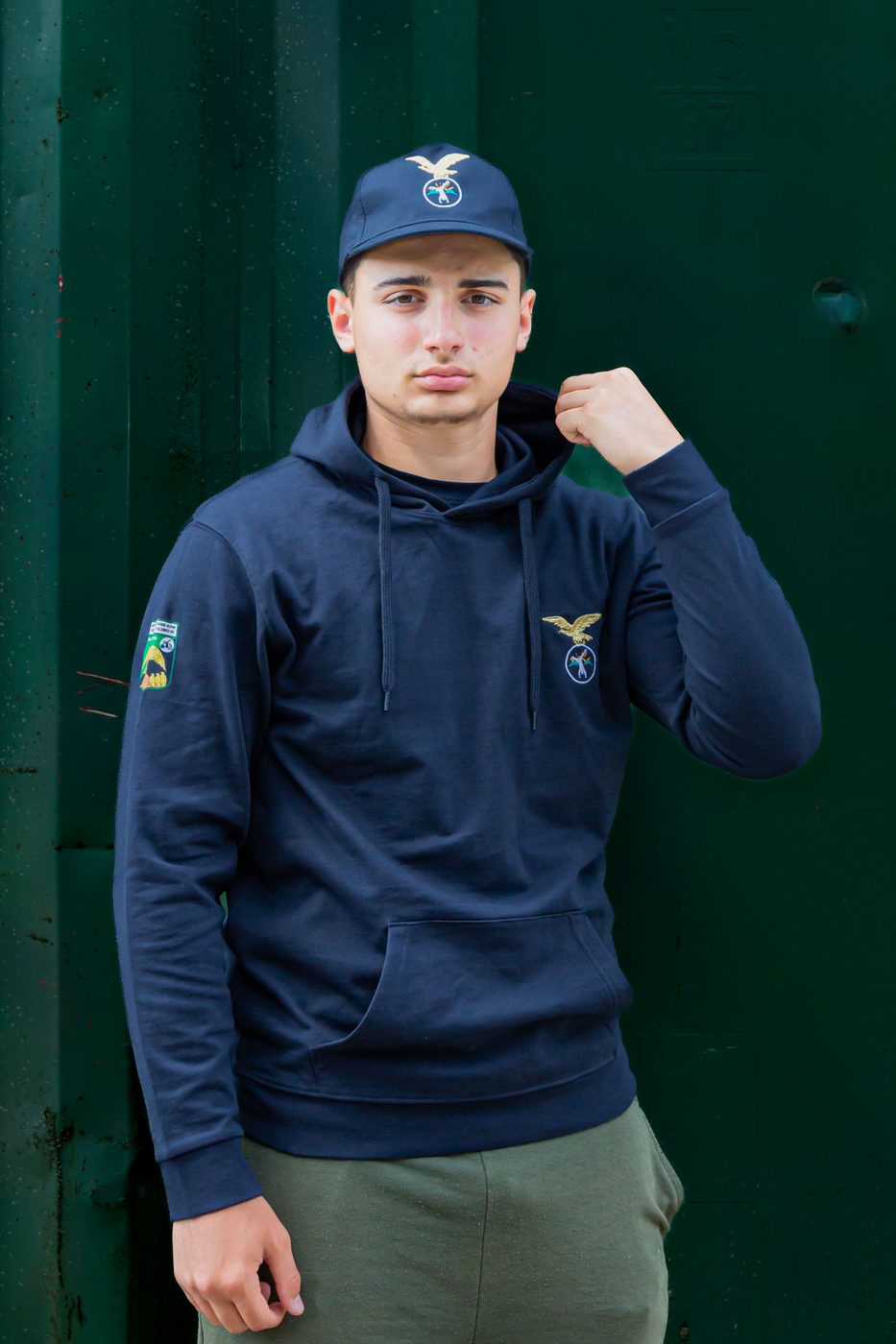 Ragazzo di tre quarti con felpa blu con cappuccio e patch sulla manica