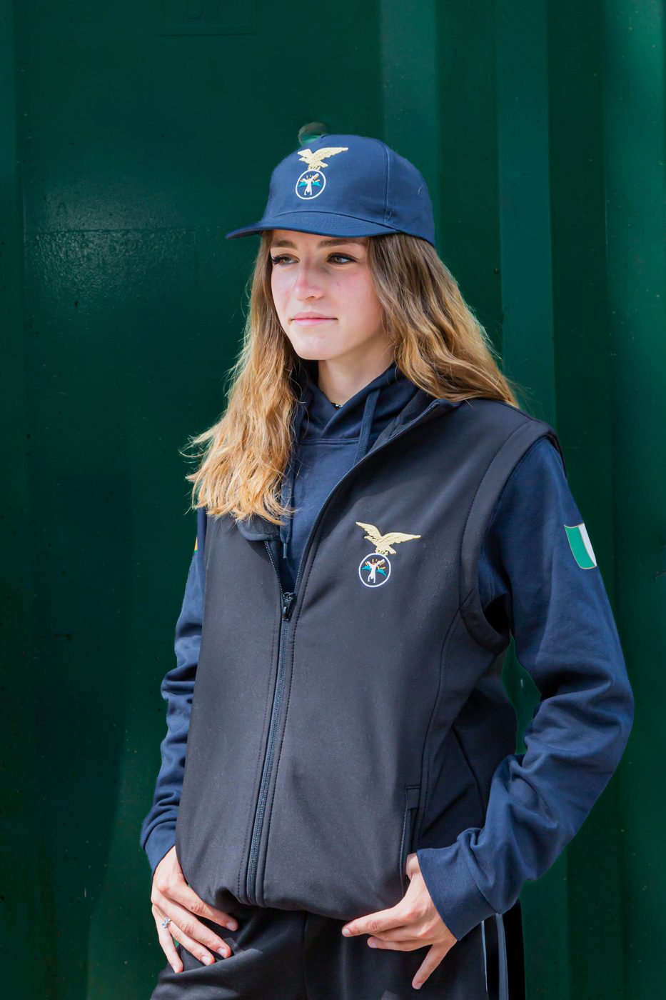 Ragazza con gilet nero sopra la felpa blu e cappellino blu