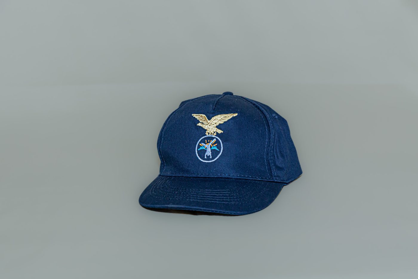 Cappellino blu visto di tre quarti, con visiera e aquila ricamata