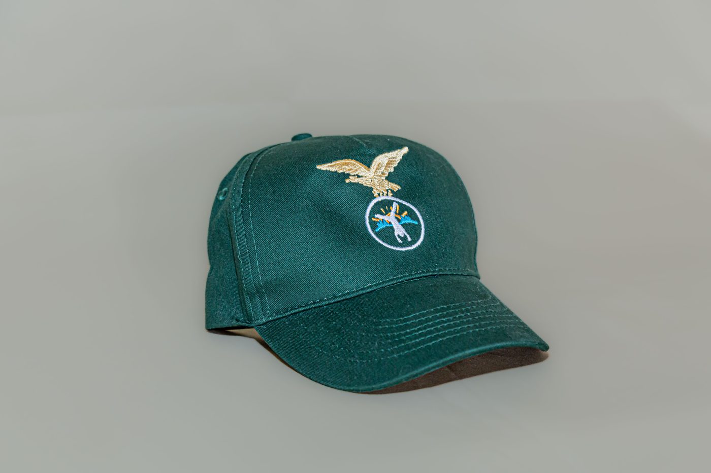 Cappellino verde visto di lato, con visiera e aquila ricamata