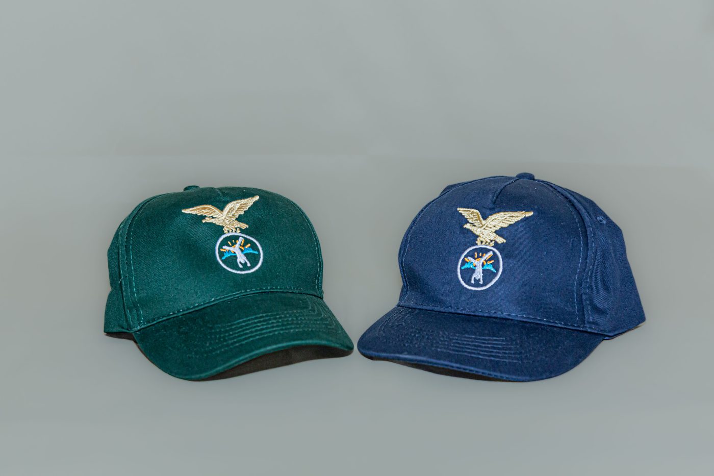 Cappellino verde e cappellino blu affiancati su fondo neutro